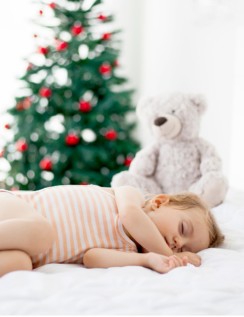 kind slaapt voor de kerstboom