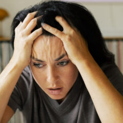 Stressed woman with head in hands at home
