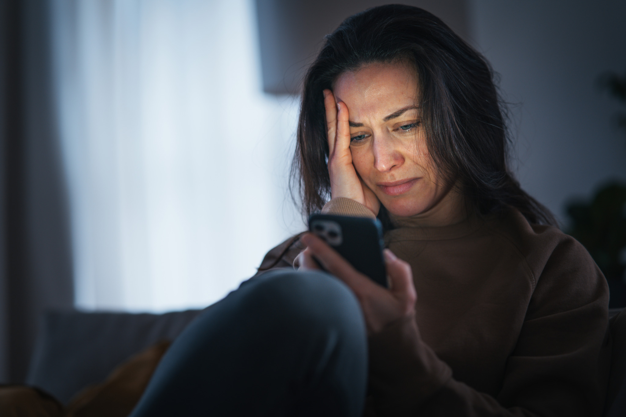 Woman reading an unpleasant text message and crying.