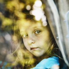 Young girl looking out window of camper van
