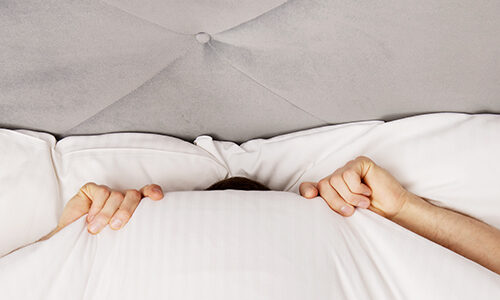 man-verbergt-hoofd-onder-lakens-2